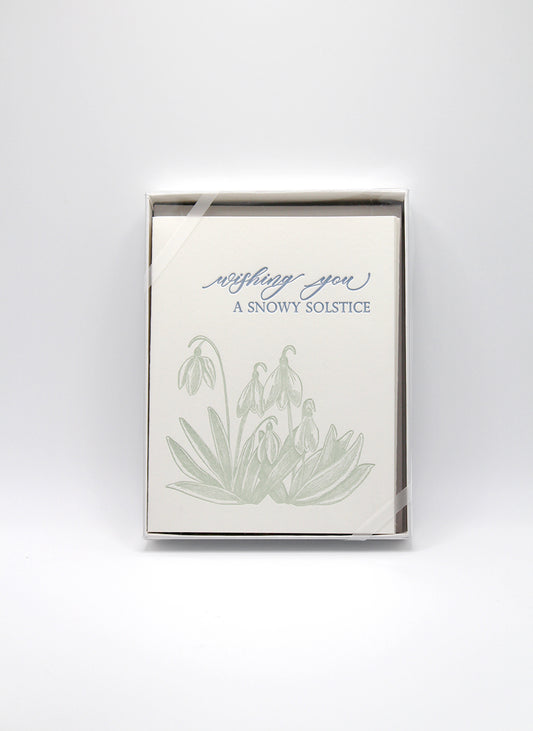 Box of letterpress holiday cards with snowdrop flowers that says "Wishing You A Snowy Solstice" by Rust Belt Love