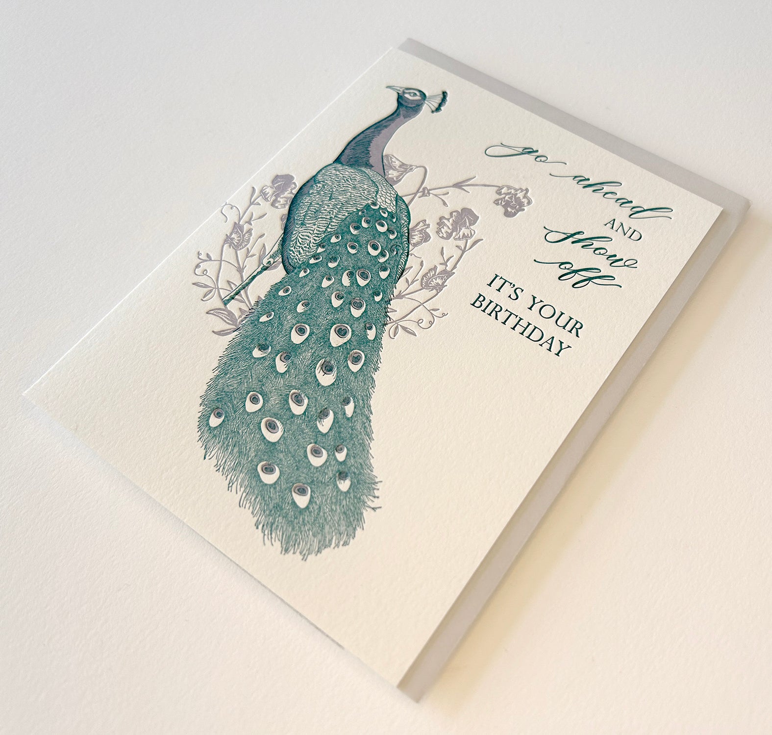 Letterpress birthday greeting card with purple and teal ink, with florals and a peacock that reads "Go ahead and show off it's your birthday", by Rust Belt Love.