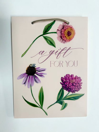 flat picture of pink birthday gift bag with florals that reads " A Gift For You" by Rust Belt Love
