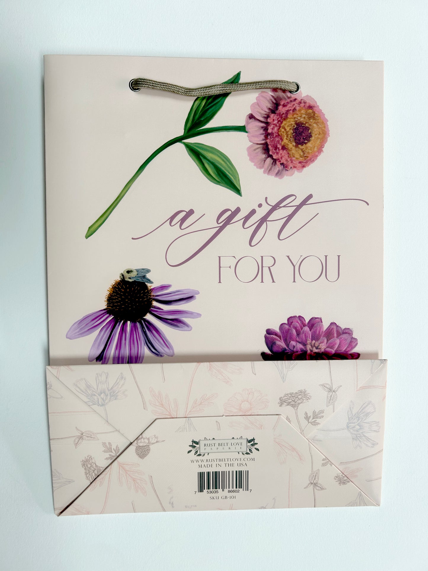 Flat picture of pink birthday gift bag with florals that reads " A Gift For You" by Rust Belt Love that also shows the bottom of the bag