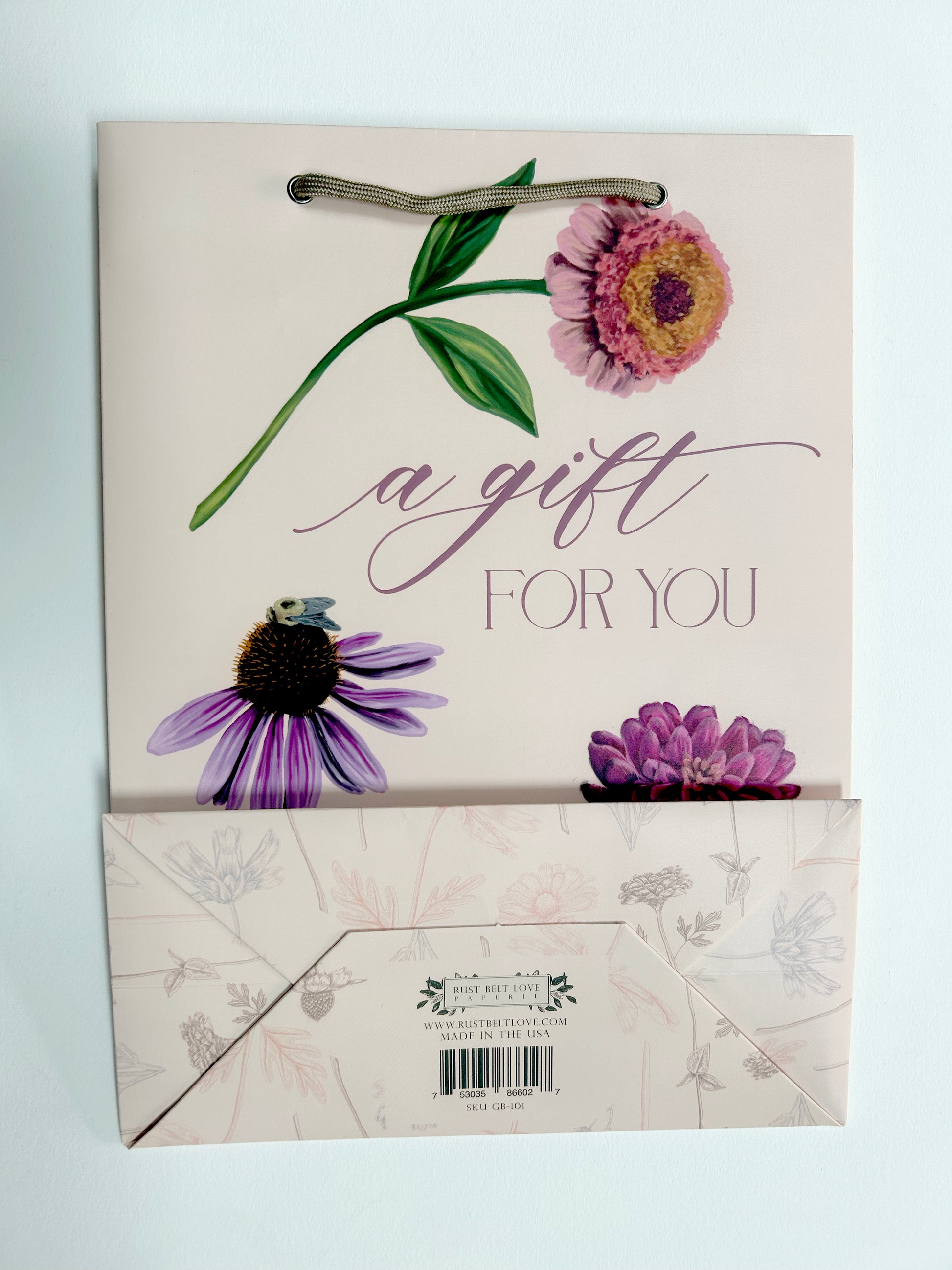 Flat picture of pink birthday gift bag with florals that reads " A Gift For You" by Rust Belt Love that also shows the bottom of the bag