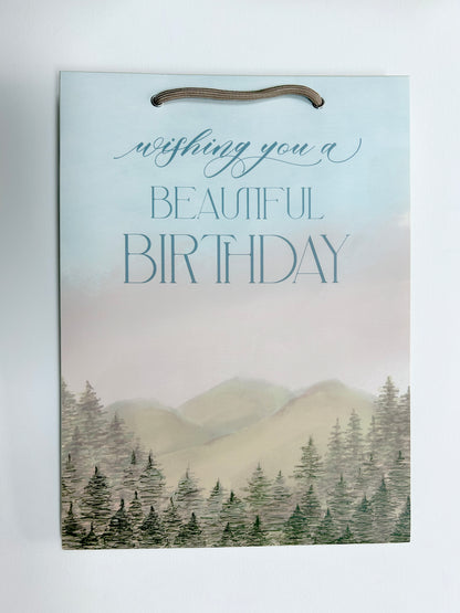 Rust Belt Love's birthday gift bag with mountain and tree scenery that reads "Wishing you a beautiful birthday"