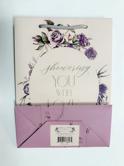 Flatlay of pink gift bag with florals that reads "Showering you with love" from Rust Belt Love, that shows the bottom