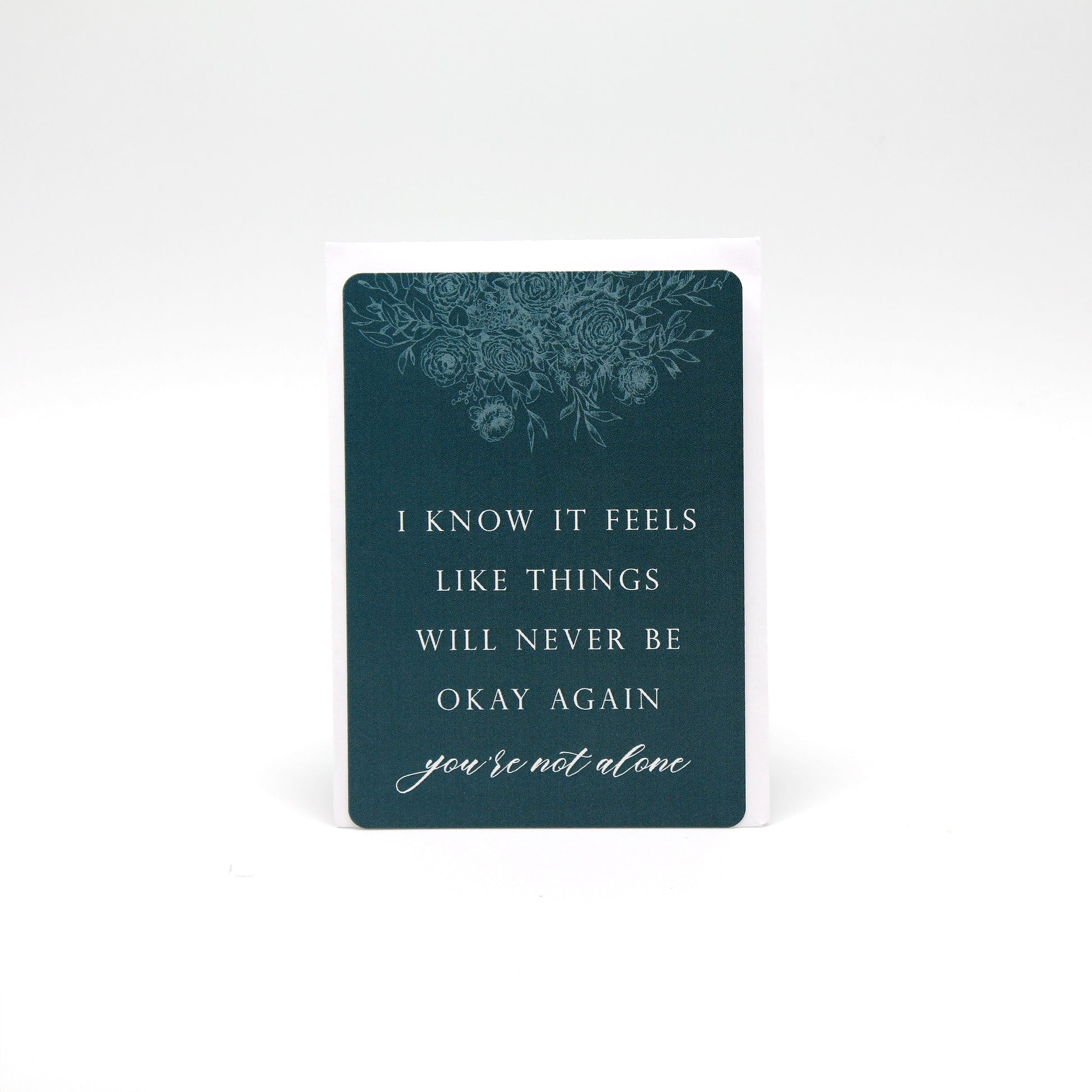 Dark teal floral minicard that reads "I know it feels like things will never be okay again you're not alone" by Rust Belt Love