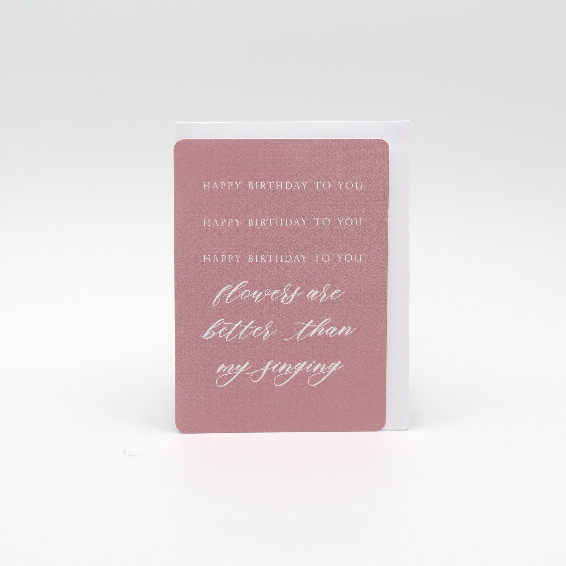 Pink minicard that reads "Happy birthday to you happy birthday to you happy birthday to you flowers are better than my singing" by Rust Belt Love