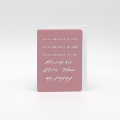 Pink minicard that reads "Happy birthday to you happy birthday to you happy birthday to you flowers are better than my singing" by Rust Belt Love