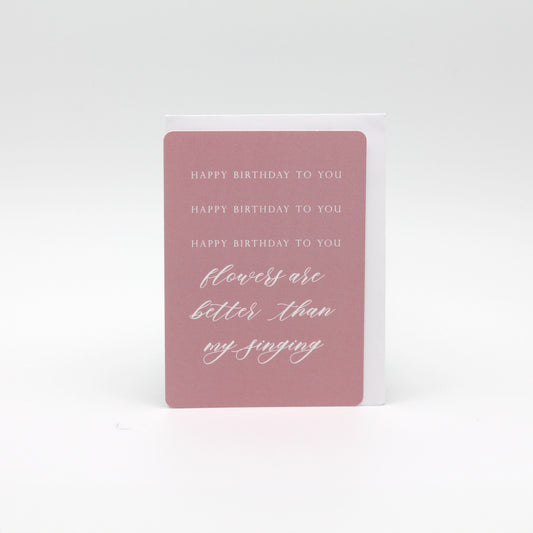 Pink minicard that reads "Happy birthday to you happy birthday to you happy birthday to you flowers are better than my singing" by Rust Belt Love