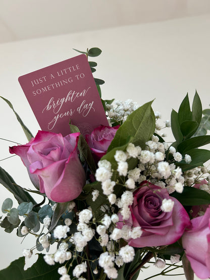 Rust Belt Love's pink floral minicard that reads "Just a little something to brighten your day" in a bouquet of flowers.