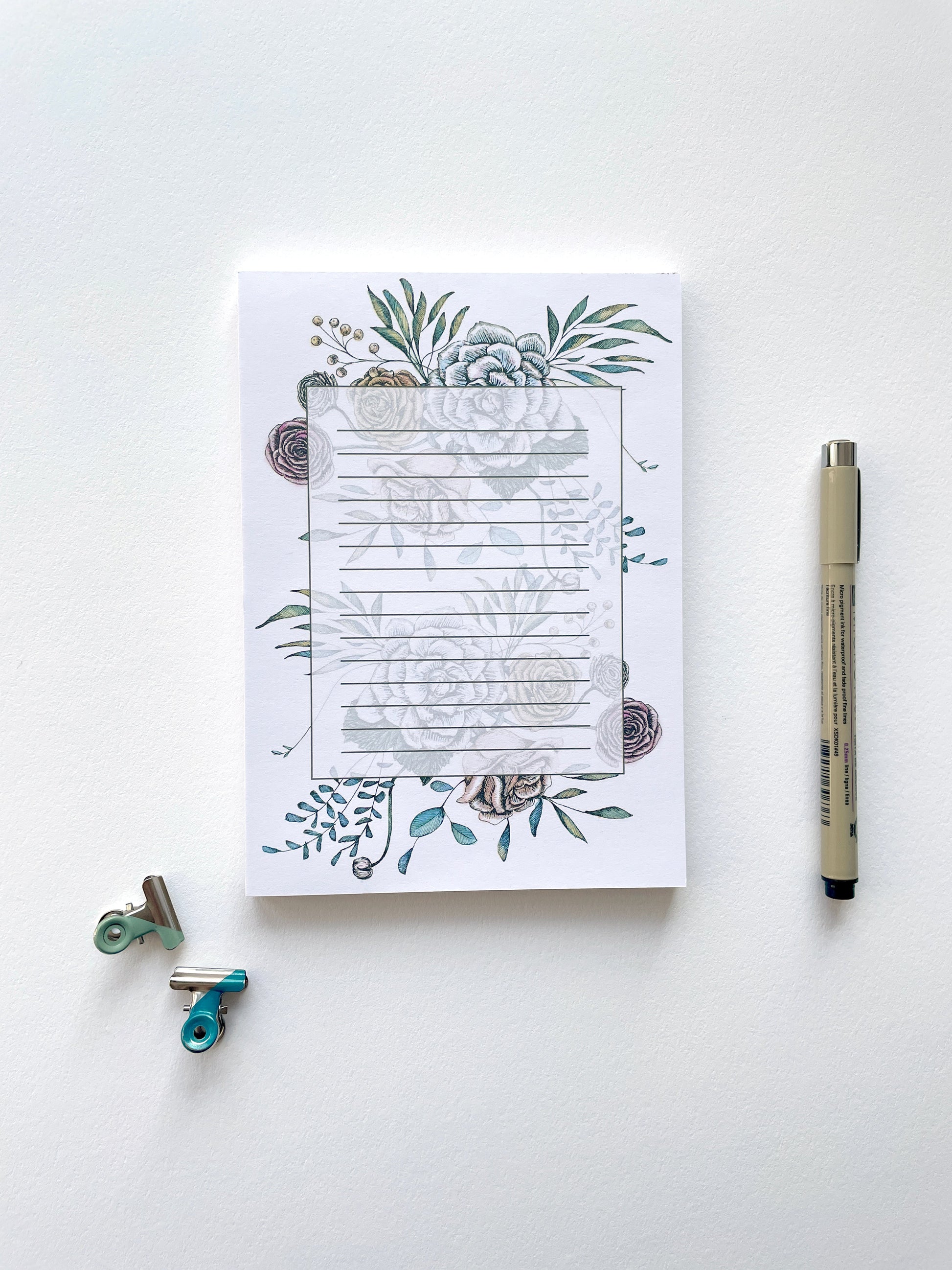 Style shot of a 5 by 7 notepad with lined sheets with multi-colored florals by Rust Belt Love