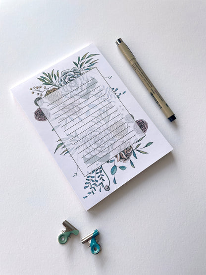 Style shot of a 5 by 7 notepad with lined sheets with multi-colored florals by Rust Belt Love