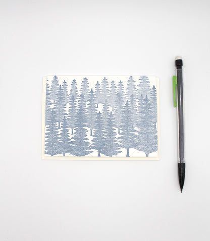 Small letterpress note card with blue evergreens on it by Rust Belt Love, with a pencil to show the size.