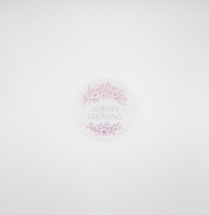 Circular pink sticker with florals that says "always growing" by Rust Belt Love