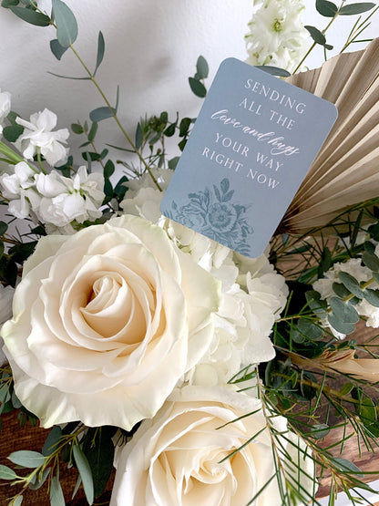 A style shot of "Sending all the love and hugs your way right now" minicard in a bouquet of flowers.